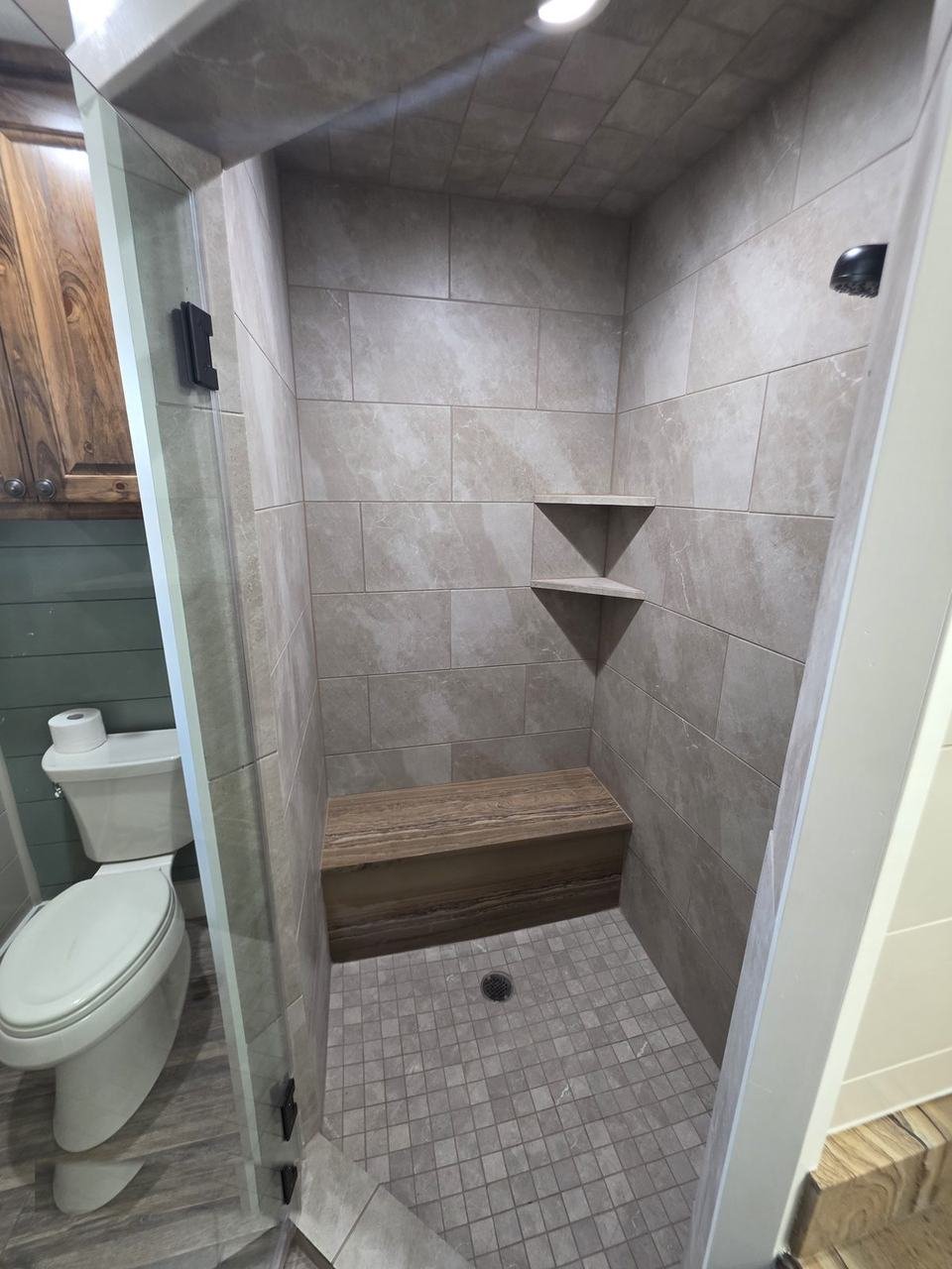 Tiled walk-in shower with a stone slab bench in a bathroom remodel in Giddings, TX