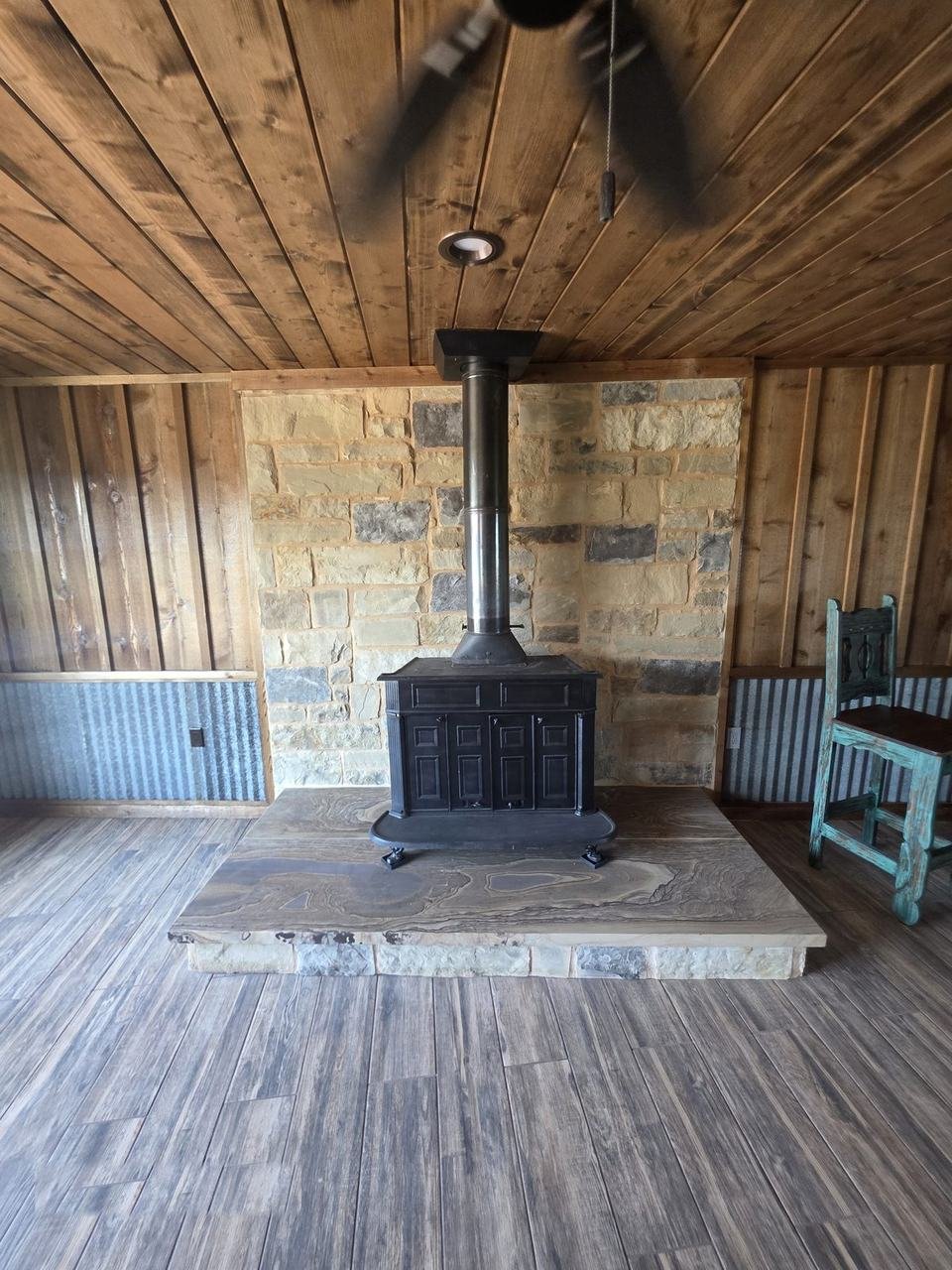 Wood stove with natural stone wall and stone slab hearth in a cabin in Giddings, TX